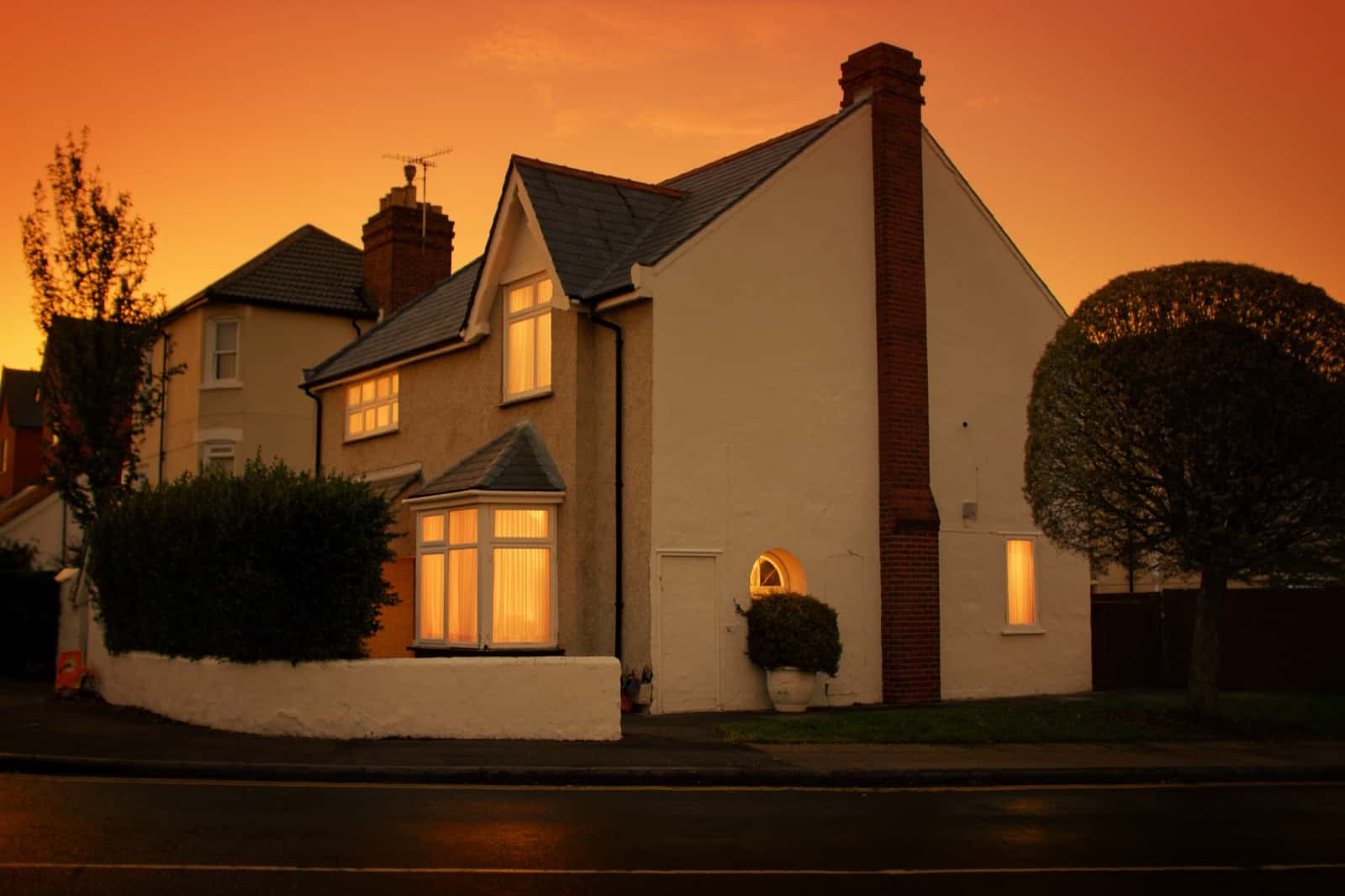 A house at dusk under a slate roof, warm light glowing in the windows