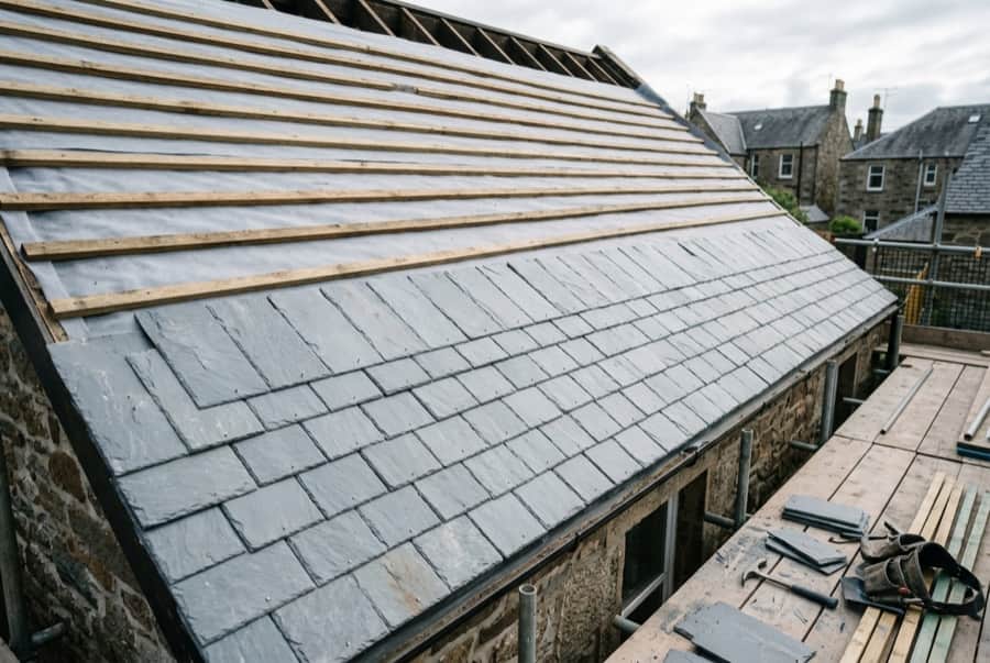 A pitched roof being covered with slate over timber battens